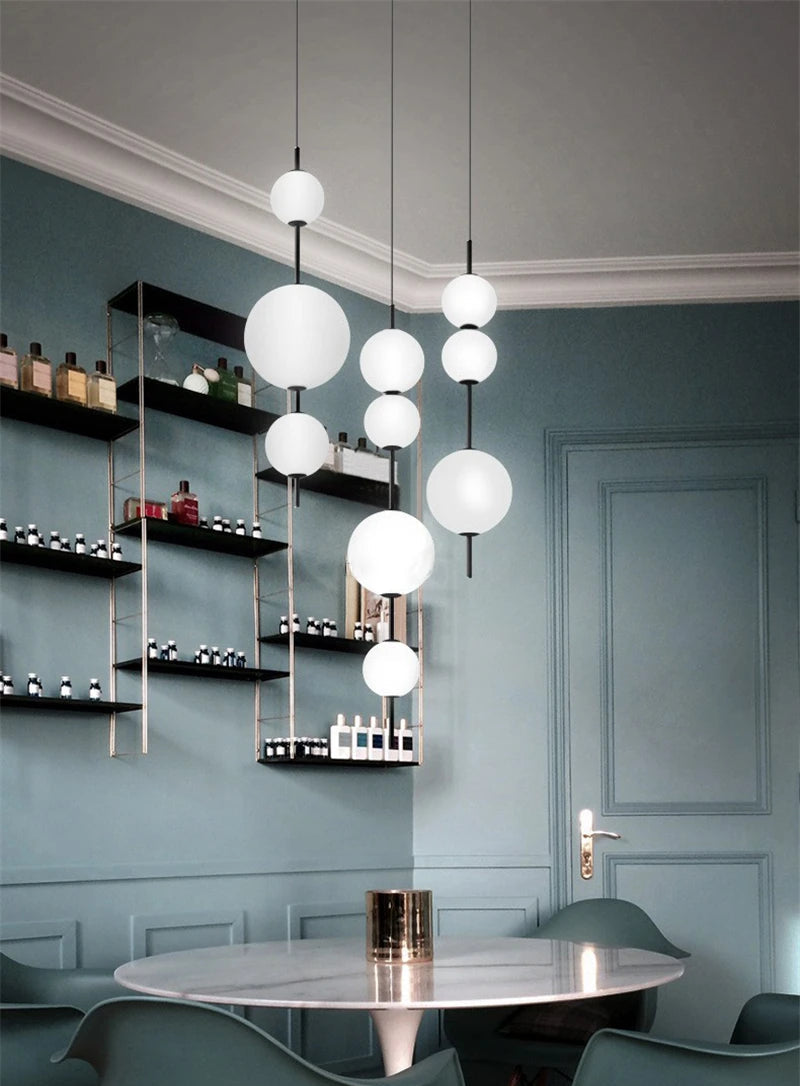 Modern chandelier hanging in a stylish room with shelves and a table.