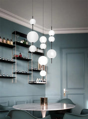 Modern chandelier hanging in a stylish room with shelves and a table.