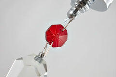 Close-up of a red crystal pendant with silver chain on a white background
