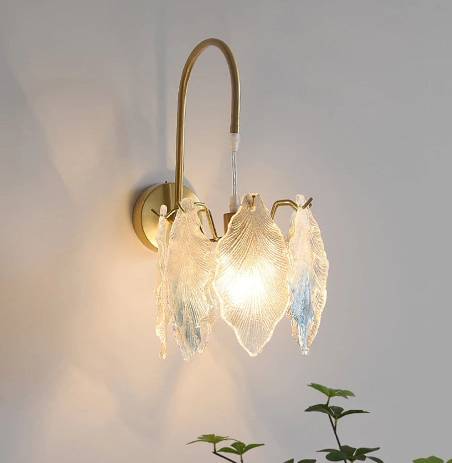 Wall-mounted light fixture with decorative glass shade on a plain wall.