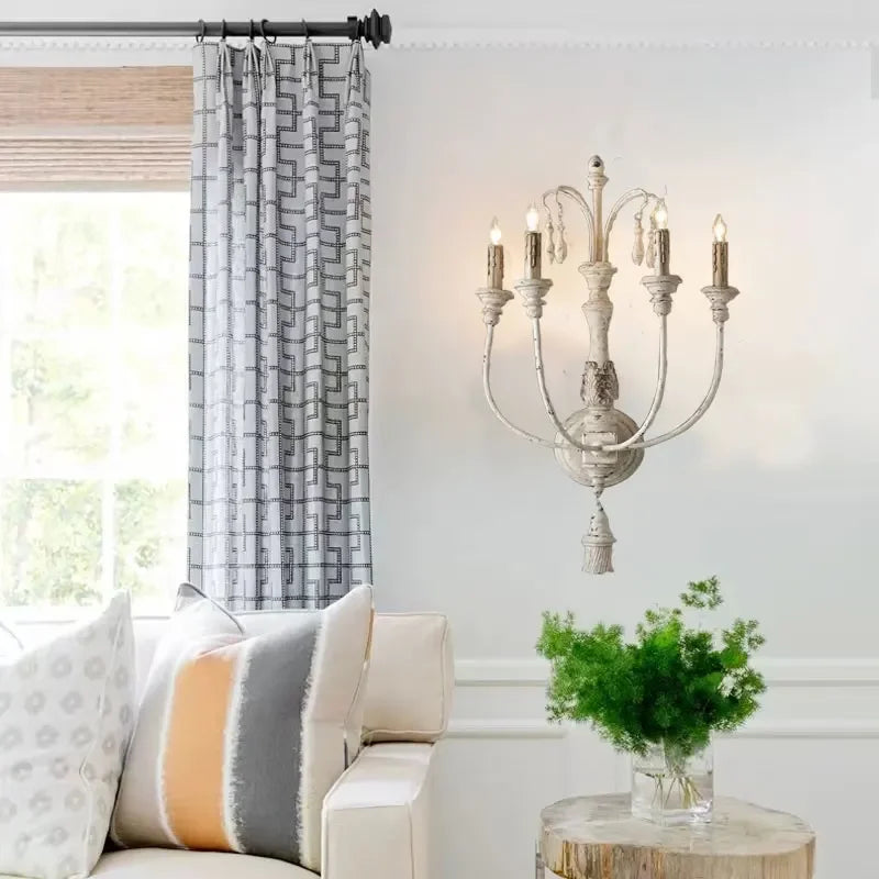 Living room with a white sofa, decorative pillows, a chandelier, and a vase of greenery.