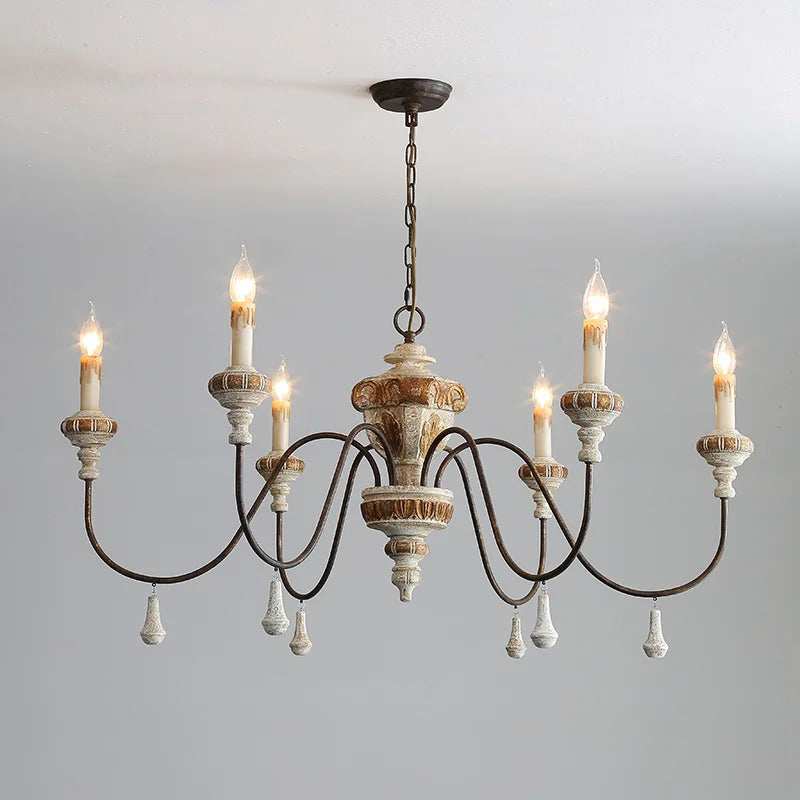 Distressed wood and iron chandelier with candle-style lights hanging from a ceiling.