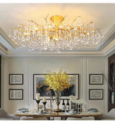Gold branch-like chandelier frame with cascading clear teardrop crystals hanging above a dining table.