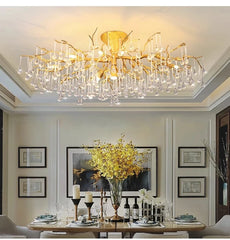 Gold branch-like chandelier frame with cascading clear teardrop crystals hanging above a dining table.