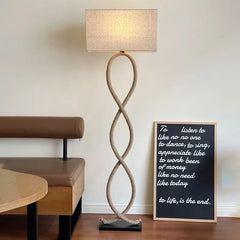 Rope-style floor lamp in a room with a bench and framed quote on the wall.
