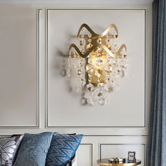 Gold wavy crystal wall sconce installed on a wall with blue curtains in the background.