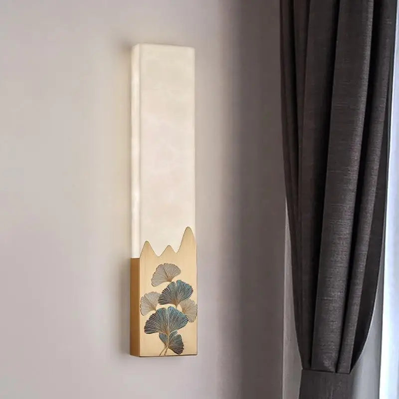 Decorative wall sconce with leaf design on a neutral wall next to a gray curtain.