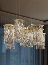 Gold crystal waterfall pendant light with cascading teardrop crystals hanging from a rectangular gold frame, illuminating a room with soft light.