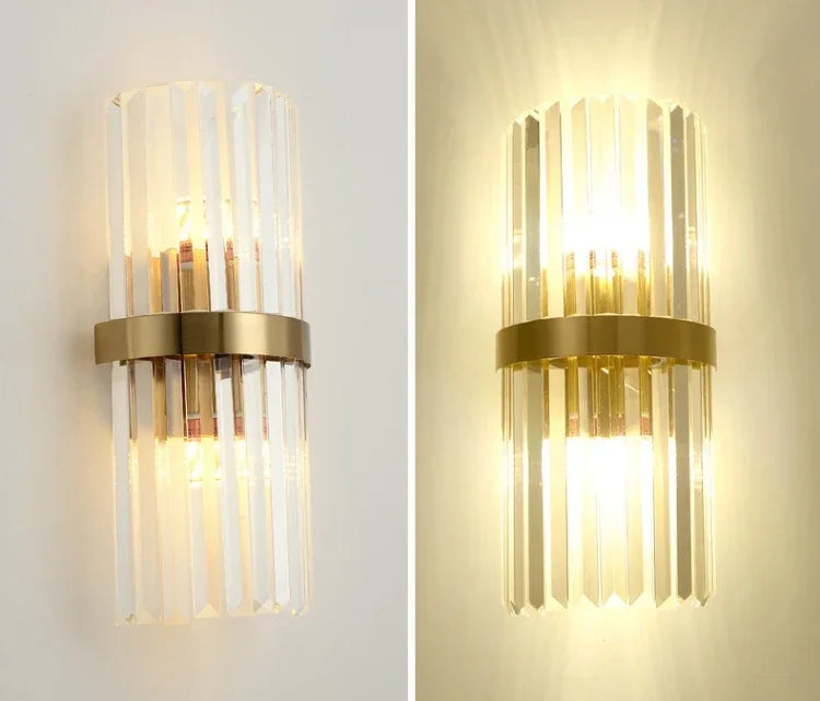 Two gold wall sconces with clear glass shades on a white wall.