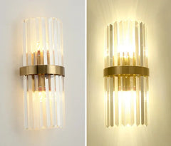 Two gold wall sconces with clear glass shades on a white wall.