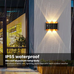 Outdoor wall light fixture on a building exterior with raindrops on the glass.