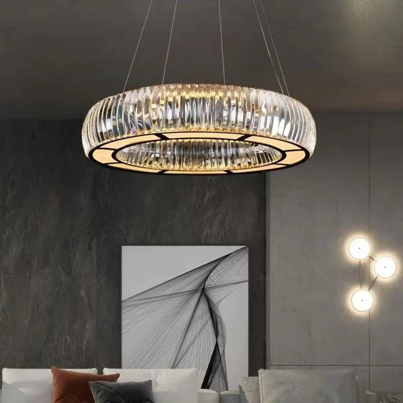 A sophisticated living room setting featuring a large, circular chrome and crystal pendant light.