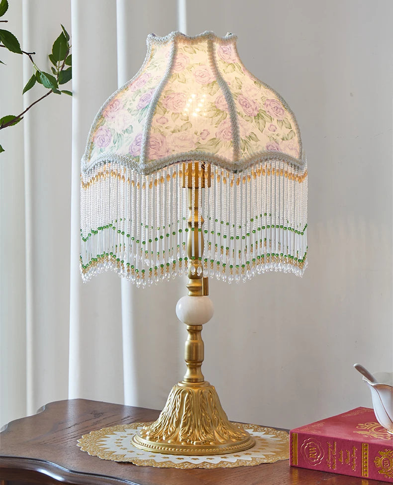 Decorative table lamp with a floral lampshade on a wooden surface.