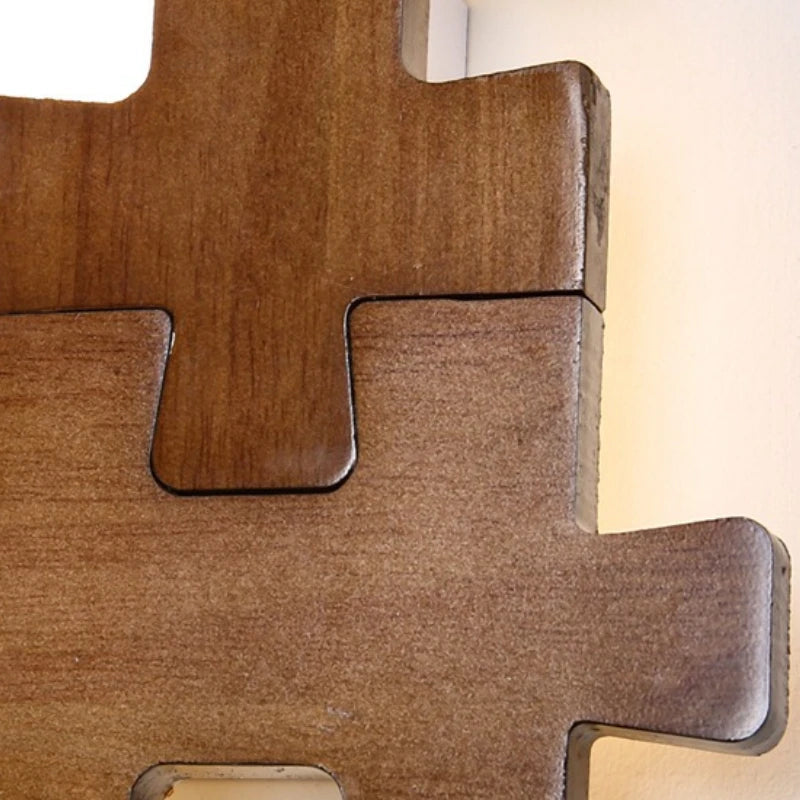 Close-up view of the interlocking wooden puzzle pieces of a wall sconce, showing the texture and joinery.
