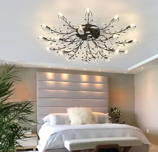 Modern chandelier in a bedroom setting with a bed and decorative pillows.