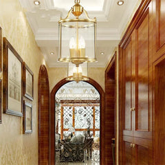 Hallway illuminated by a gold lantern pendant light, featuring an arched doorway and wooden cabinets.