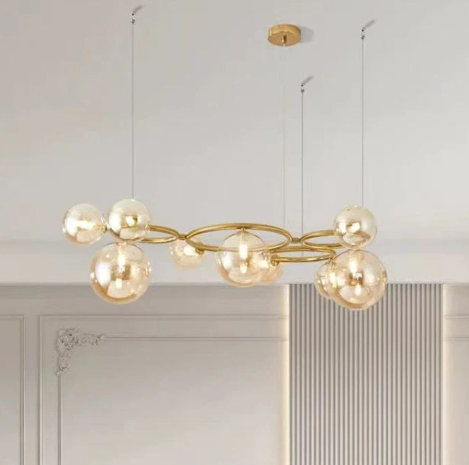 Modern gold chandelier hanging in a room with white walls and a decorative mirror.