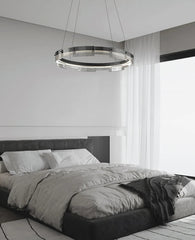 Modern bedroom with a chandelier hanging above a bed.