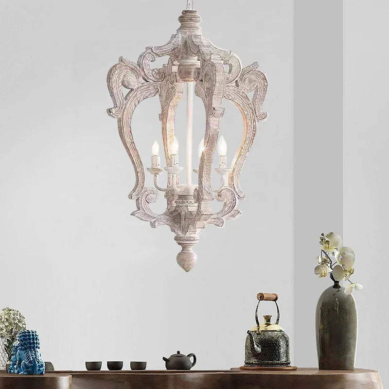 Decorative chandelier hanging above a wooden table with teacups and a teapot.
