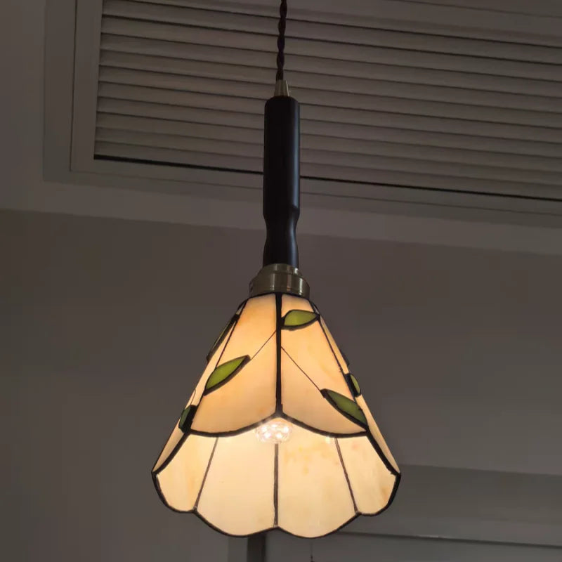 Stained glass pendant light with leaf design on a neutral background