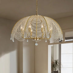 View of a gold crystal waterfall chandelier hanging in a well-lit room with a window.