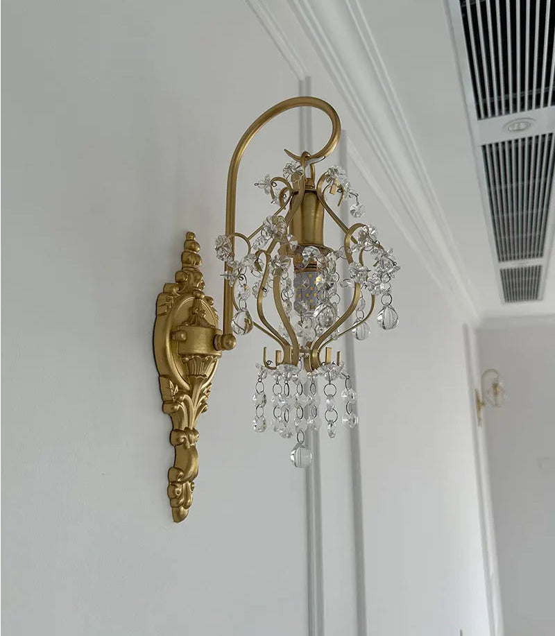 Decorative gold wall sconce with crystal accents on a white wall.