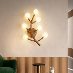 Wooden wall sconce with multiple lights on a beige wall, with a green chair and wooden side table in the foreground.