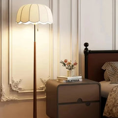 Floor lamp in a bedroom setting with a nightstand and books.