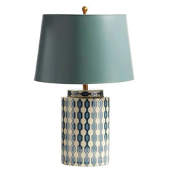 A blue ceramic table lamp with a geometric pattern and a light blue fabric shade against a white background.