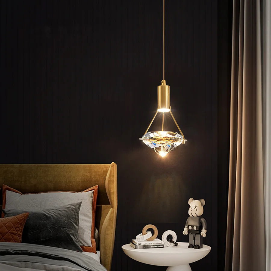 Modern bedroom with a gold pendant light, bed, and small table with decorative items.