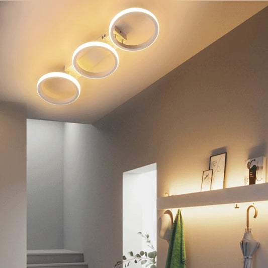 White LED ceiling light with three interconnected rings mounted on a hallway ceiling.