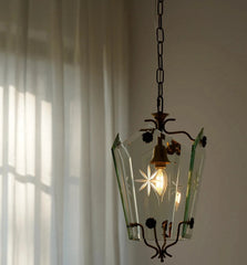 Vintage-style pendant light with glass shade and brass fixture against a neutral wall.