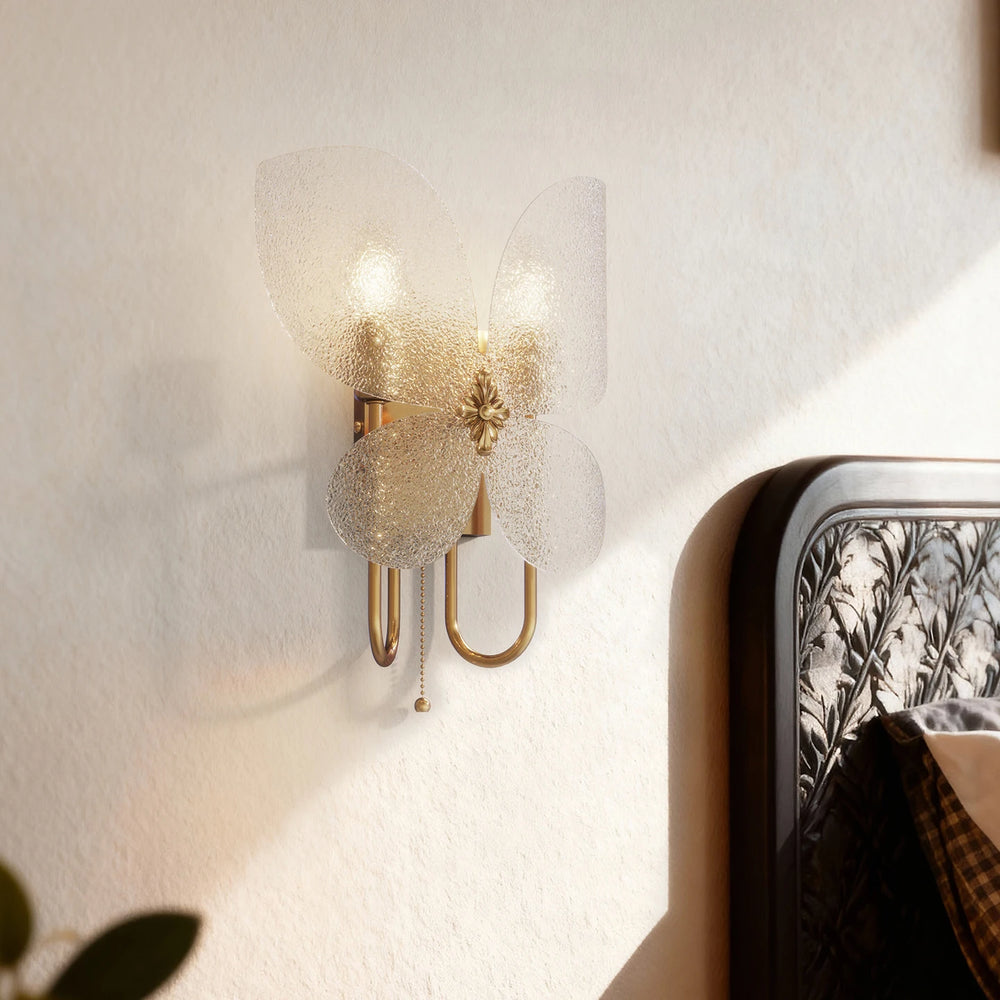 Gold butterfly wall sconce installed next to a bed, showing its decorative appeal in a bedroom setting.