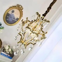 Close-up of a gold ornate chandelier with clear teardrop crystals cascading down.
