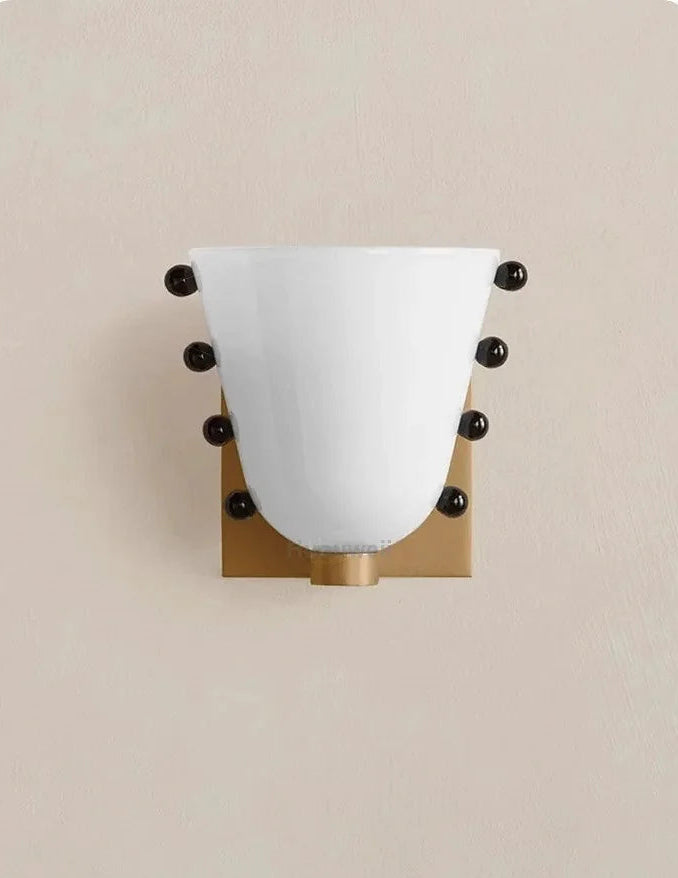 Wall sconce with white glass shade and gold fixture on a beige background