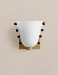 Wall sconce with white glass shade and gold fixture on a beige background