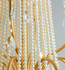 Close-up of a chandelier with pearl-like beads and gold accents.