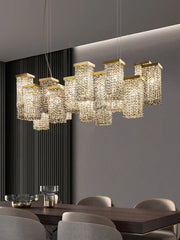 A linear arrangement of gold crystal pendant lights with cascading crystals, installed over a dark wood dining table.