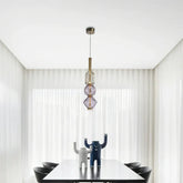 Modern pendant light with a clear glass orb shade and brushed gold hardware hanging over a dining table.