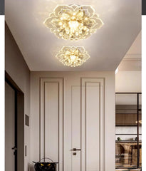 A close-up view of two gold and crystal floral semi-flush ceiling lights in a modern interior hallway setting.