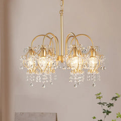 The gold crystal chandelier viewed from a side angle, showing the arrangement of the crystal strands and the overall silhouette.
