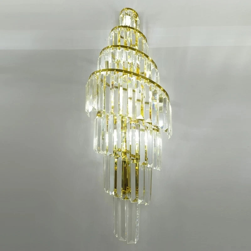 Close-up of a gold wall sconce featuring a spiral design with hanging K9 crystals, showcasing the reflective qualities of the gold frame and clear crystals.