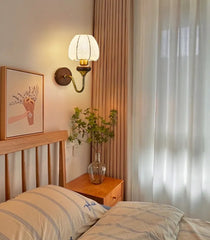 Bedroom with wooden headboard, striped pillows, wall lamp, and framed picture.