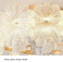 Detail of the glass flower shades on the gold ceiling light, highlighting the textured petals and central light source.