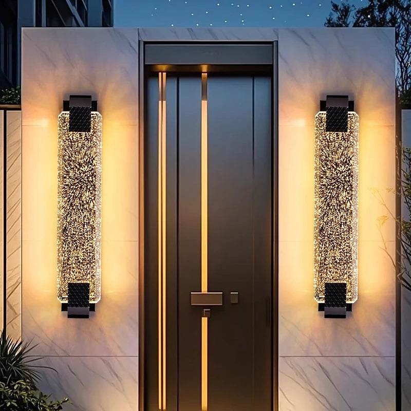 Close-up of a gold wall sconce featuring a tall, rectangular bubble crystal shade and metallic accents.