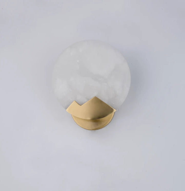Wall sconce with gold fixture and white glass shade on a light gray background