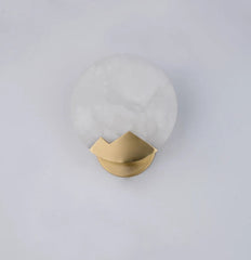 Wall sconce with gold fixture and white glass shade on a light gray background