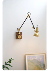 Angle view of the brass adjustable swing arm wall sconce, showing the wooden backplate and knob switch.