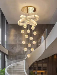 Modern chandelier hanging in a staircase area with glass walls.