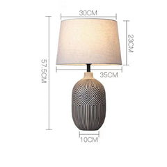 Table lamp with geometric design on base and plain lampshade, shown with dimensions.